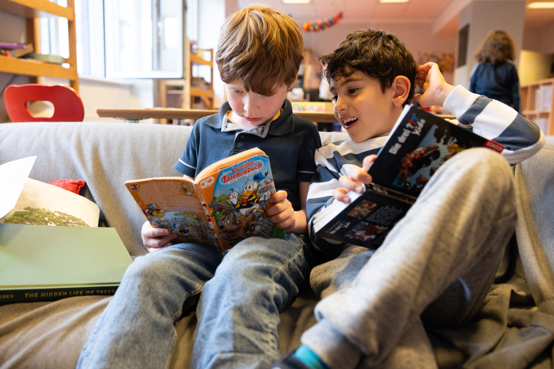 Drei Kinder sitzen nebeneinander uns lesen gemeinsam Bücher